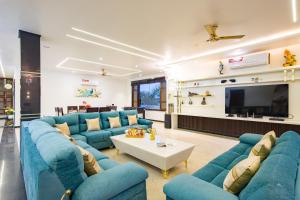 a living room with blue couches and a tv at ELIVAAS Ivory estate 5 BHK Farm with Pvt Pool, Gazebos & Lounge Area in Manjhāoli