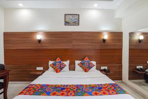 une chambre avec un grand lit avec des oreillers colorés dans l'établissement FabHotel The Grace Inn Near Galleria Market & Golf Course Road, à Gurgaon
