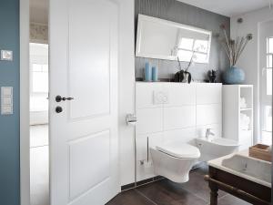 a white bathroom with a toilet and a sink at Ferienhaus Elsa 180 qm in Rust +35 photos