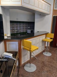 una cocina con 2 sillas amarillas y una barra en Qurum Heights Hotel, en Mascate