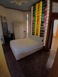 1 dormitorio con cama blanca y pared colorida en Qurum Heights Hotel, en Mascate