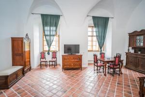 a living room with a tv and a table and chairs at zámek Kolštejn - hotel Chateau Goldenstein in Branná