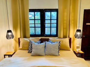 a bedroom with a bed with pillows and two windows at THARA PHLU BUNGALOWS Koh Chang in Ko Chang