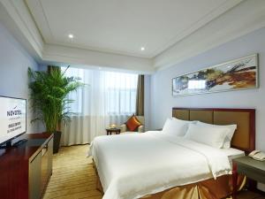 a bedroom with a large white bed and a desk at Novotel Guiyang Panjiang in Guiyang
