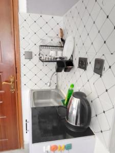 - une cuisine avec évier et pot sur le comptoir dans l'établissement Acacia Sky, à Nakuru