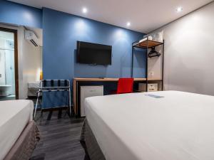 a room with two beds and a desk with a tv at ibis Styles Belem Nazare in Belém