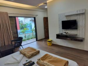 a living room with a flat screen tv and a table at Mudra Resort in Nagaon