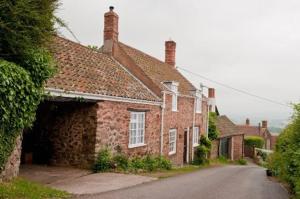 an old brick house with a road in front of it at Moonfleat in West Quantoxhead