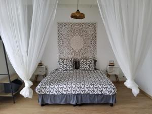 a bedroom with a large bed with white curtains at LE RUBINJO Case fleurie in Saint-Benoît +13 photos
