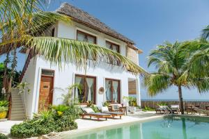 a villa with a swimming pool in front of a house at Babu Villas in Jambiani