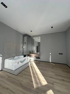una grande stanza bianca con una vasca da bagno su un pavimento in legno di Royal jacuzzi apartment on Krehivska 10 st a Lviv