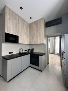una cucina con mobili bianchi e un piano di lavoro nero di Royal jacuzzi apartment on Krehivska 10 st a Lviv