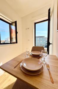 a wooden table with plates and wine glasses on it at Loving Porto Cozy Flat by MyMoradia in Porto