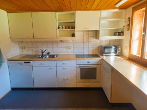 アウ・イム・ブレゲンツァーヴァルトにあるHaus Kanisfluhの白いキャビネットとシンクと電子レンジを備えたキッチン +15枚の写真