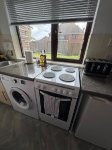 a kitchen with a stove and a sink and a window at Thorpe Park Studio - Detached Stay & Free Gated Parking in Thorpe