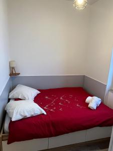 a bed with two pillows and a red blanket at Le Nid Joli in Argelès-Gazost