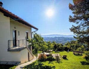 a house with a balcony and a view of the mountains at Apartma Hiša na Ravnah with hot tub in Pišece