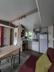 a living room with a table and a kitchen at Mobil home 4 personnes au pied du Grand Massif à Samoëns in Samoëns +3 photos
