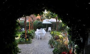 ein Garten mit weißen Tischen und Stühlen und einem Sonnenschirm in der Unterkunft Hotel Lodi in Rom