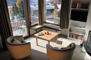 a living room with two chairs and a table and a large window at Chesa Arnica A5 in La Punt-Chamues-ch