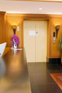 un hall d'entrée de bureau avec une porte vitrée et des fleurs dans l'établissement The Grand Imperial, à Ban Song Hong