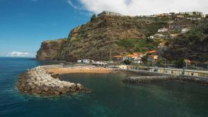 a group of people on a beach next to the ocean at SeaSalt Whisper - Guest House in Calheta