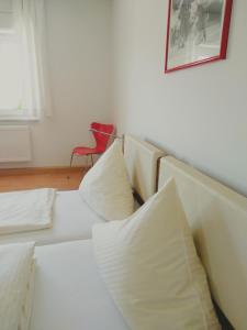 a white couch with pillows in a room with a red chair at Dorfschänke DEGGENDORF Hotel & Apartmenthaus in Deggendorf