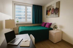 a bedroom with a green bed and a desk with a laptop at V Ajax Warsaw Bed&Breakfast ROOMS in Warsaw