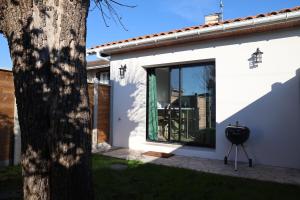 a white house with a window and a grill at Le Jardin de Sauge in Le Teich