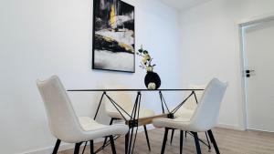 a dining room table with white chairs and a vase on it at Crystal North Deluxe Apartments - Modern Comfort & Style in Voluntari
