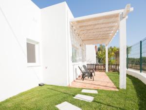 a patio with two chairs under a wooden pergola at Tavira Monte in Tavira