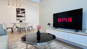 a living room with a flat screen tv on a entertainment center at Crystal North Deluxe Apartments - Modern Comfort & Style in Voluntari