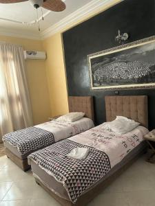 two beds in a bedroom with a picture on the wall at Meknès 2 Perle de Meknes in Meknès +15 photos