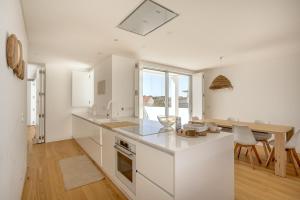 una cucina con banconi bianchi e tavolo e una sala da pranzo di Ericeira Modern & Bright with Pool by Homing a Barril