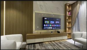 a living room with a tv and two white chairs at The Emeritus Apartments in Akure