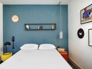 a bedroom with a white bed and a blue wall at Hôtel ibis Styles Clermont-Ferrand Gare in Clermont-Ferrand
