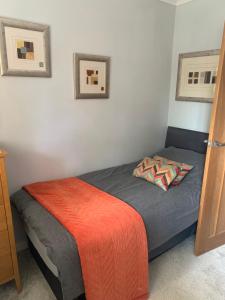 a bedroom with a bed with an orange and gray blanket at Commuters Haven perfect for conferences airport and offices near airport in Cove