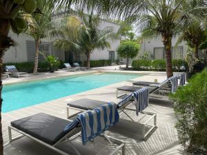 a swimming pool with lounge chairs and palm trees at Résidence Gabriel in Sali Nianiaral