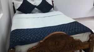 a bed with a blue and white comforter and pillows at H M G service apartment in Sringeri