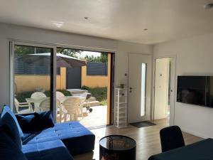 a living room with a blue couch and a sliding glass door at Maison au Pays de Fontainebleau in Vulaines-sur-Seine