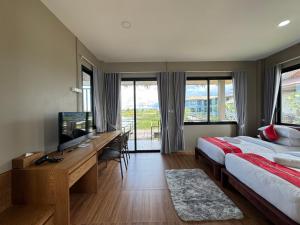 a bedroom with a bed and a desk with a television at Nabua Thalenoi Resort นาบัว ทะเลน้อย รีสอร์ท in Ban Thale Noi