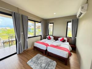 a bedroom with two beds and a balcony at Nabua Thalenoi Resort in Ban Thale Noi