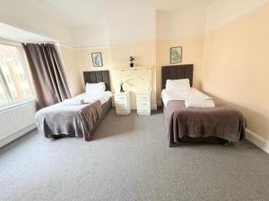 a bedroom with two beds and a window at Large 4 Bedroom Sleeps 8, Spacious Apartment for Contractors and Holidays near Bedford Centre - 1 FREE PARKING SPACE & FREE WIFI in Bedford +16 photos