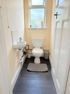 a bathroom with a toilet and a sink and a window at Large 4 Bedroom Sleeps 8, Spacious Apartment for Contractors and Holidays near Bedford Centre - 1 FREE PARKING SPACE & FREE WIFI in Bedford