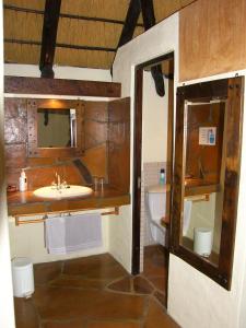 a bathroom with a sink and a mirror and a tub at Roidina Safari Lodge in Omaruru