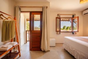 a bedroom with a bed and a door and windows at Vila Dádiva Jeri in Jericoacoara