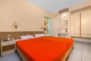 a bedroom with an orange bed and a bathroom at Pavlos Hotel in Kos Town