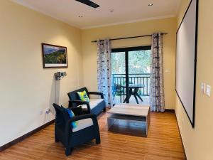 a living room with chairs and a table and a balcony at Sren Self Catering - One Bedroom II in Anse Royale