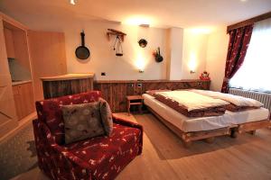 1 dormitorio con 1 cama y 1 silla en Garnì Ladin, en Vigo di Fassa