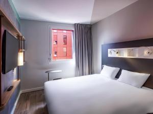 a bedroom with a large white bed and a window at ibis budget Saint-Étienne Centre Gare Châteaucreux in Saint-Étienne +67 photos